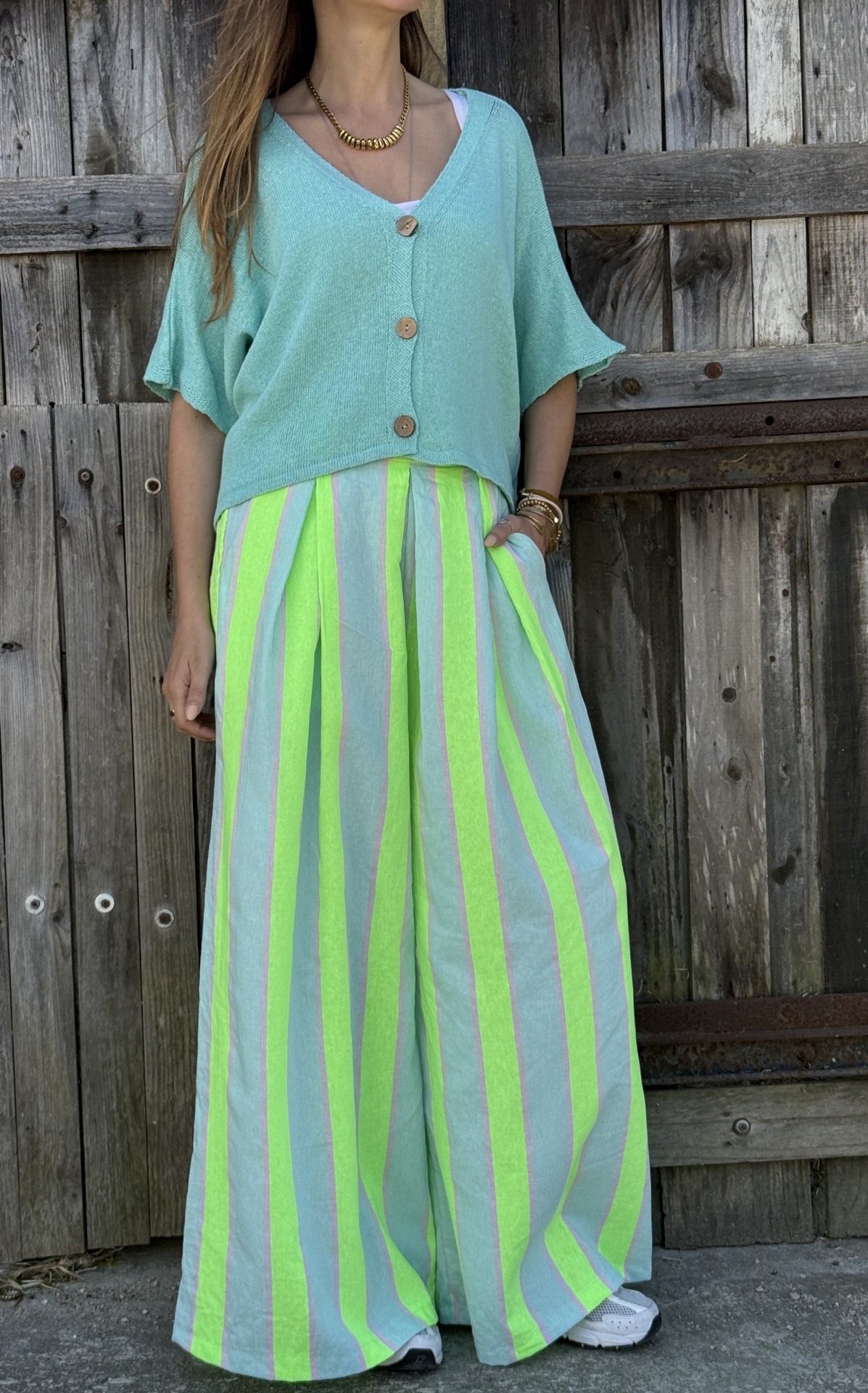 Pessoa com camisola verde água e calças largas riscas verde fluor e azul claro