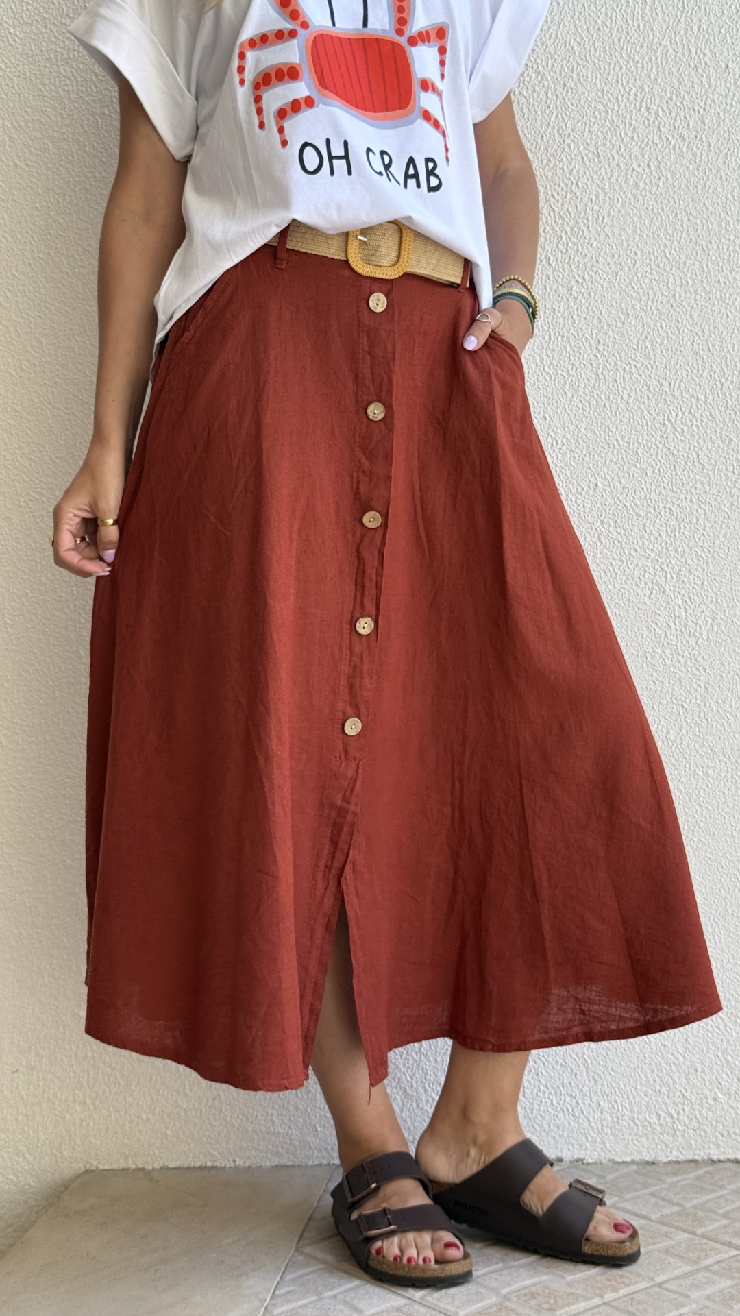 Saia midi terracota de linho com botões e cinto bege combinada com T-shirt branca com caranguejo e texto