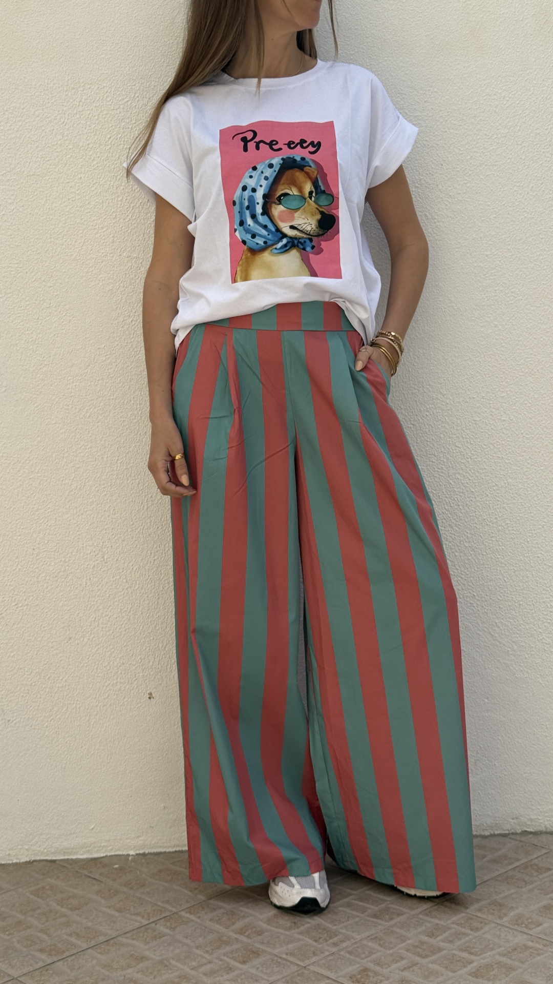 T-shirt branca com estampa de cão e calças largas riscas verticais verdes e vermelhas.