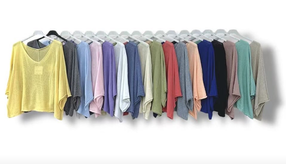 Camisolas coloridas leves penduradas em cabides numa linha