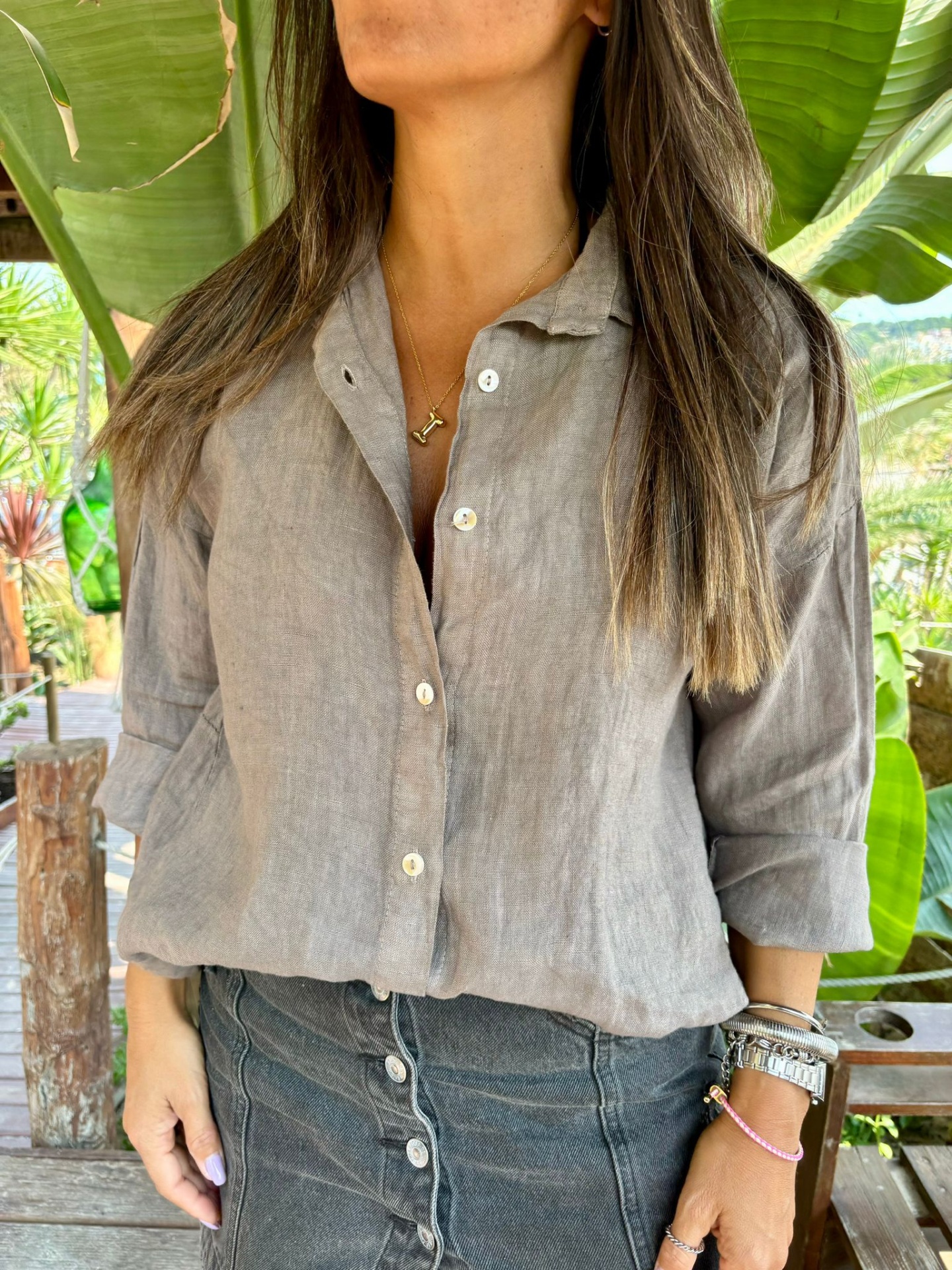 Blusa feminina cinza claro com botões e saia cinza escura com botões em ambiente natural