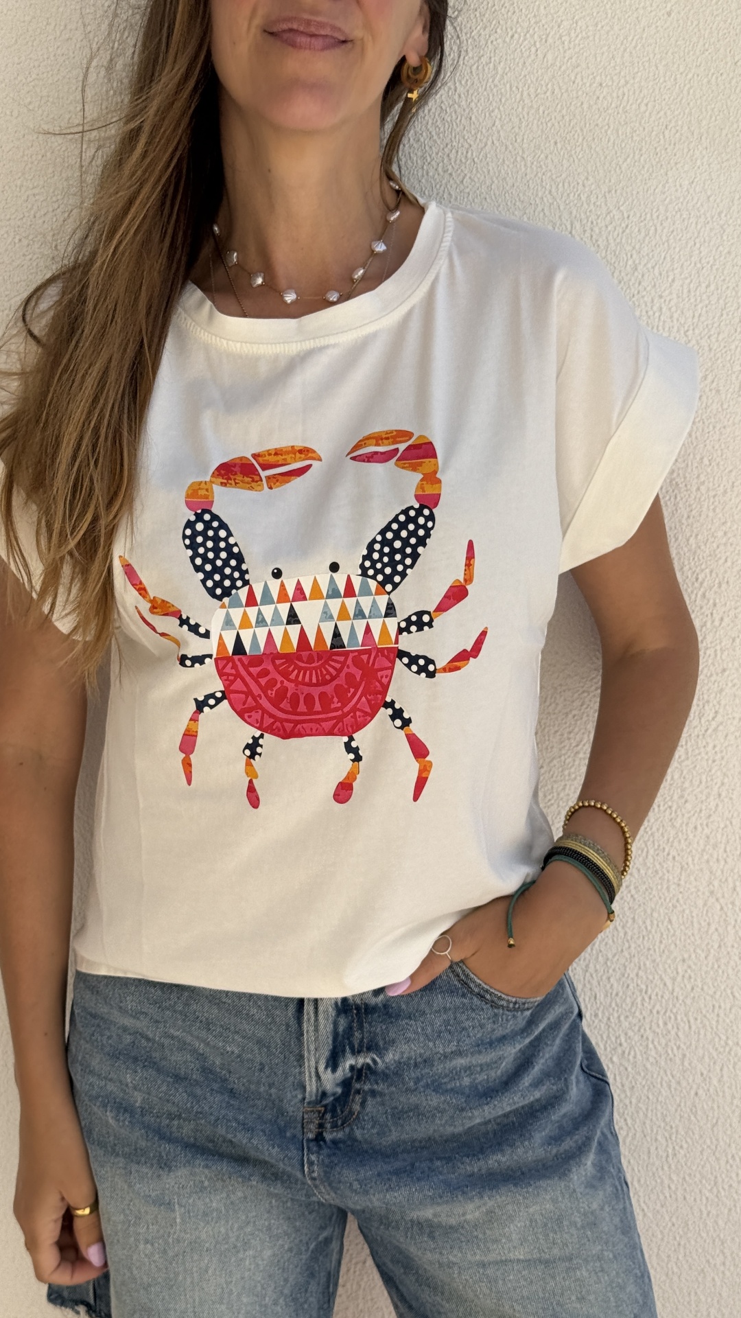 T-shirt branca com estampa colorida de caranguejo e jeans azuis