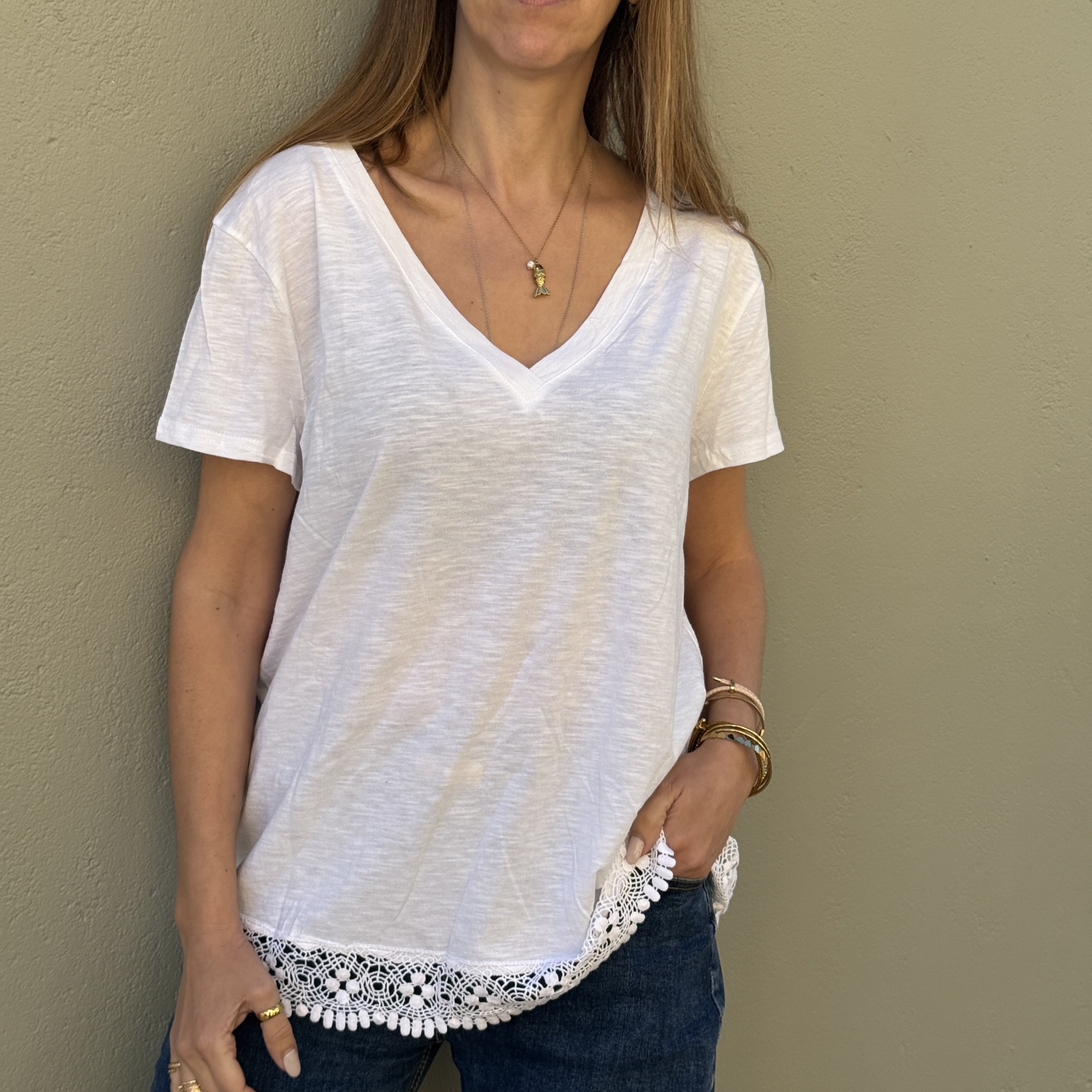 T-shirt branca feminina com decote em V e renda na bainha.