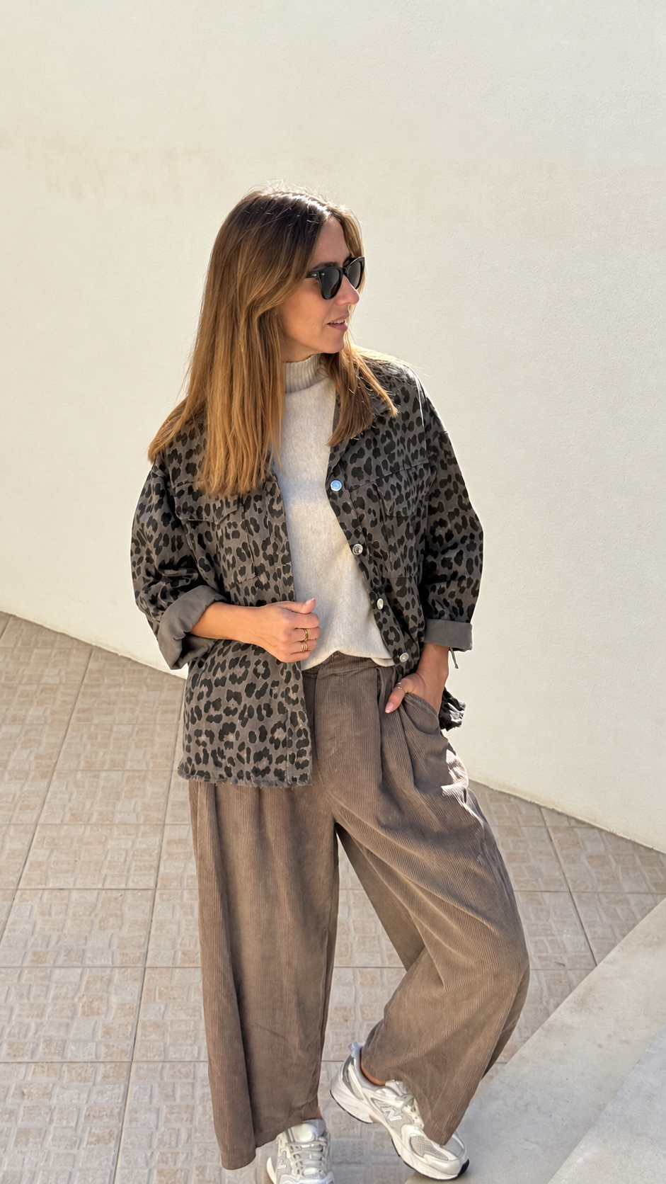 Mulher com casaco animal print e calças castanhas largas com ténis brancos