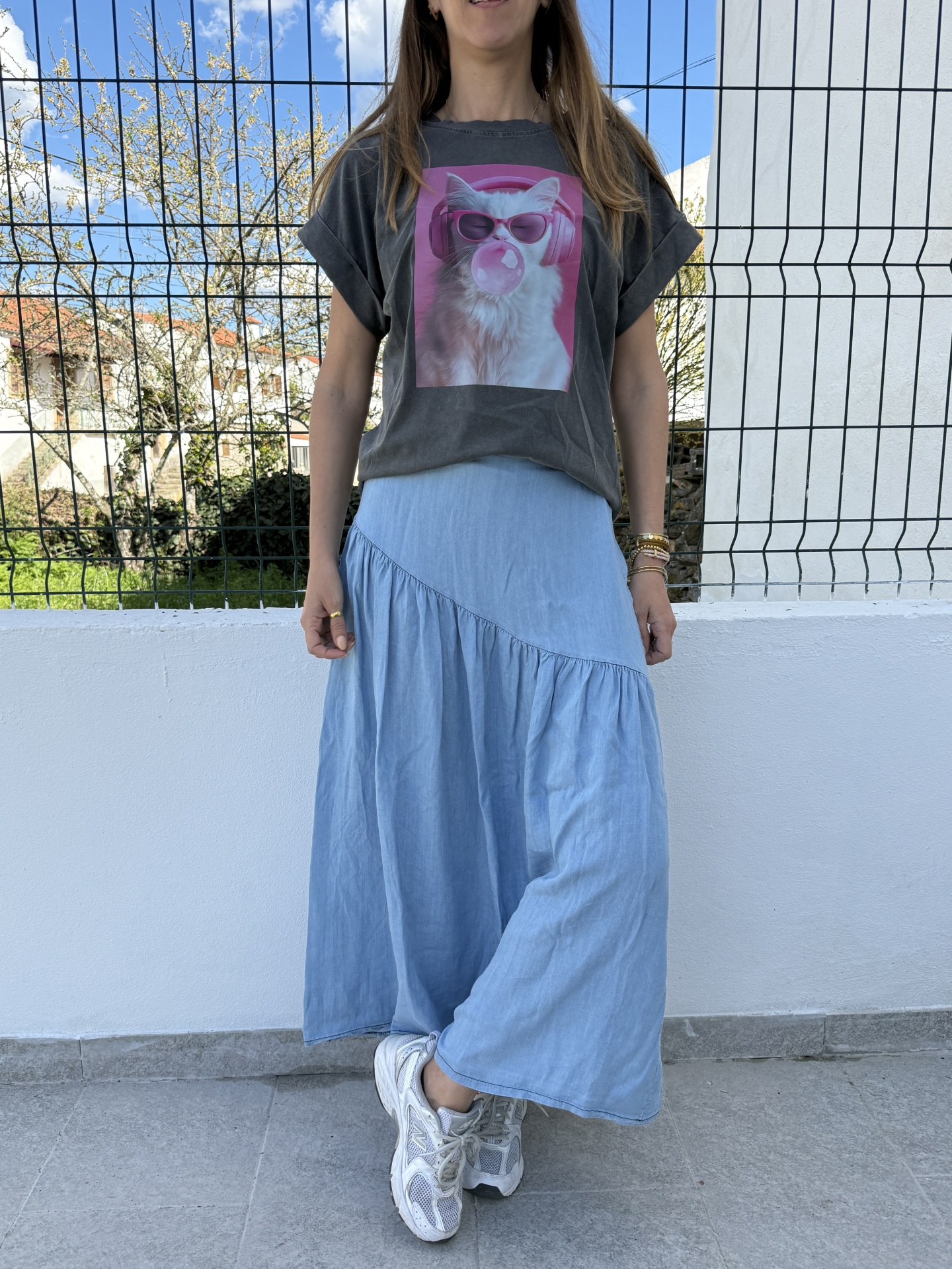Mulher com t-shirt cinzenta com estampa de gato e saia azul clara