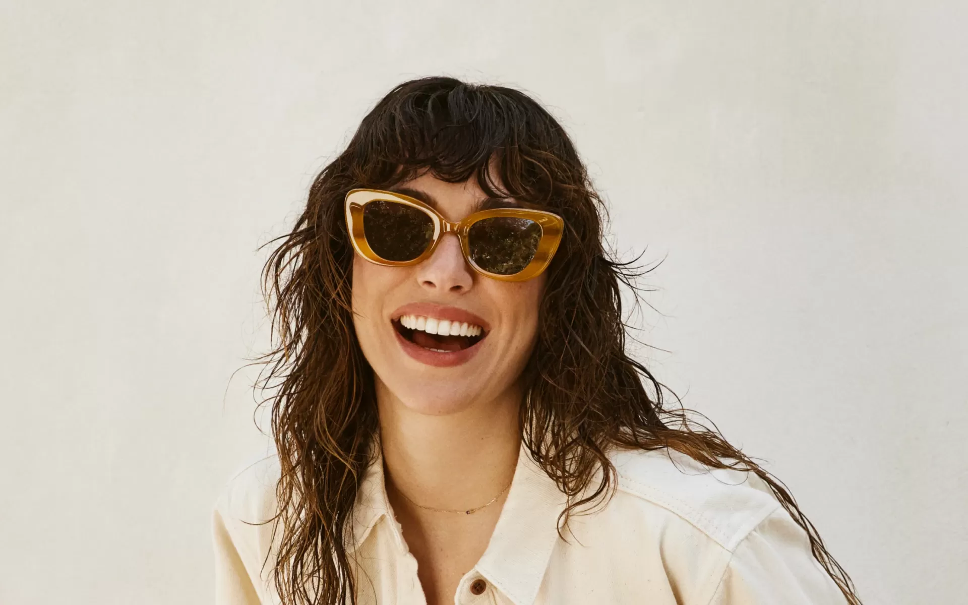 Mulher a usar óculos de sol amarelos com lentes escuras e camisa clara