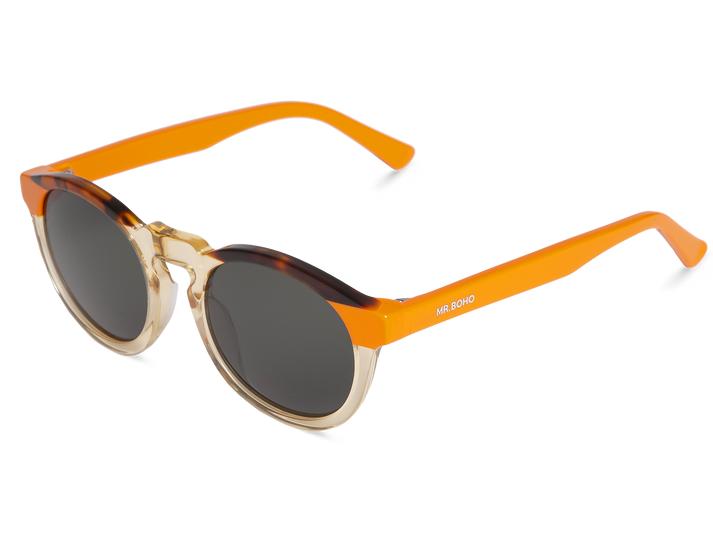 Óculos de sol com lentes redondas e armação em várias tonalidades de castanho e âmbar, hastes alaranjadas com texto branco.