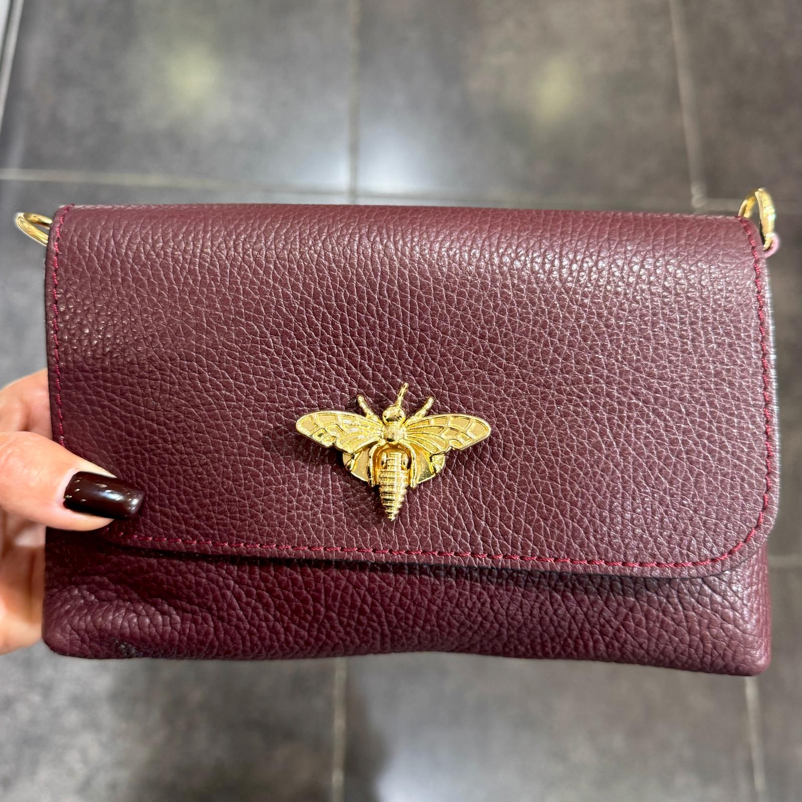 Carteira de pele vinho com fecho em forma de abelha dourada e alça fina dourada