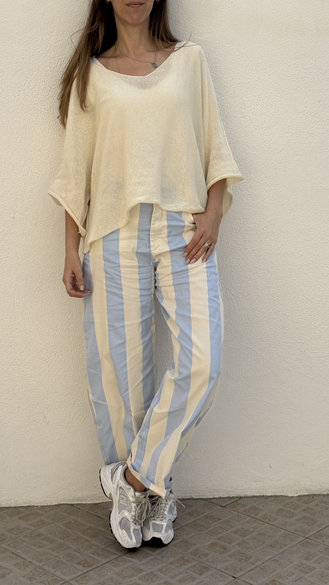 Mulher com camisola creme e calças riscas azuis e creme