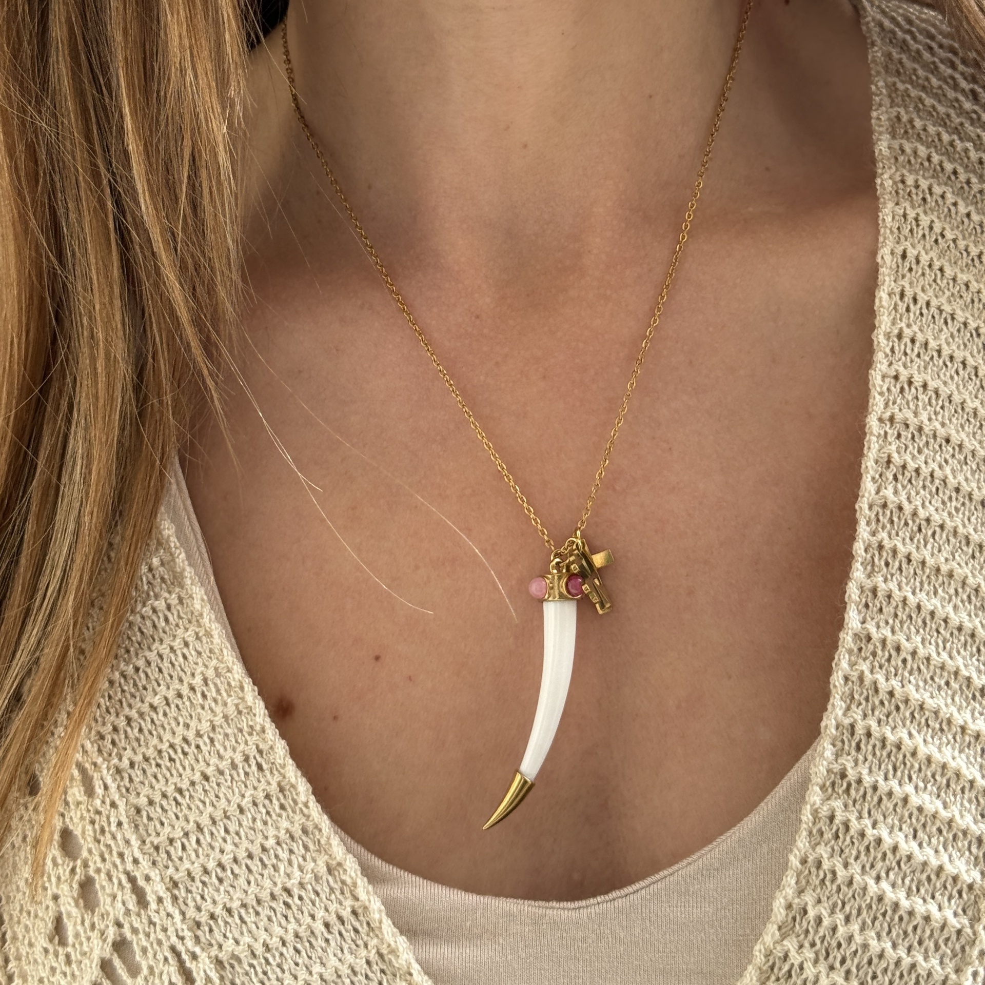 Colar com pendente em formato de presa branca com detalhes dourados e pedras rosa