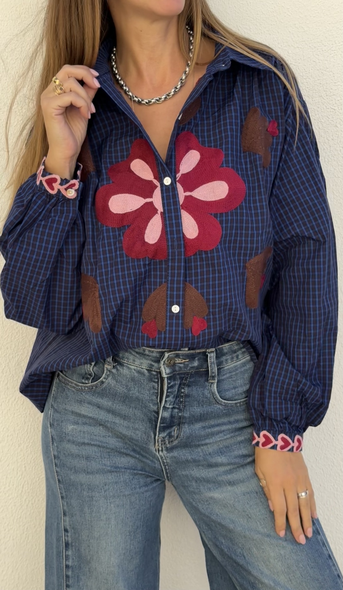 Camisa azul escura xadrez com bordados florais vermelhos e rosa, usada com jeans azul claro