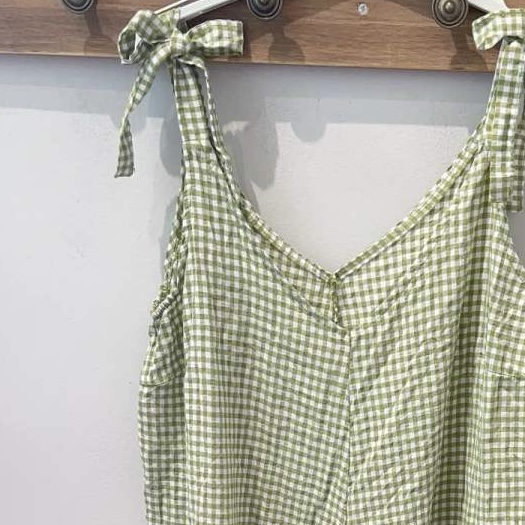 Vestido xadrez verde claro e branco com laços nas alças pendurado na parede