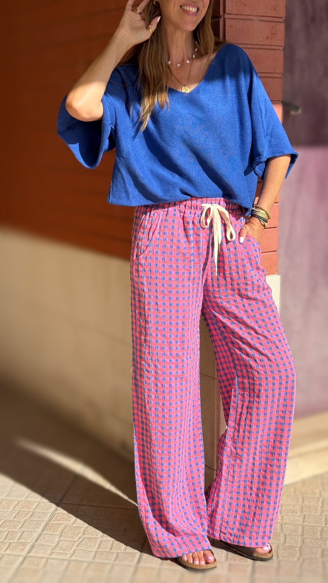 Mulher a usar camisola azul e calças xadrez rosa e azul ao ar livre