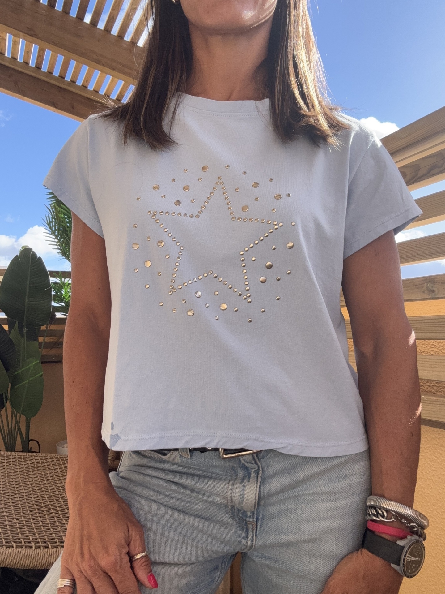 T-shirt branca com estrela dourada em rebites, jeans e pulseiras no braço