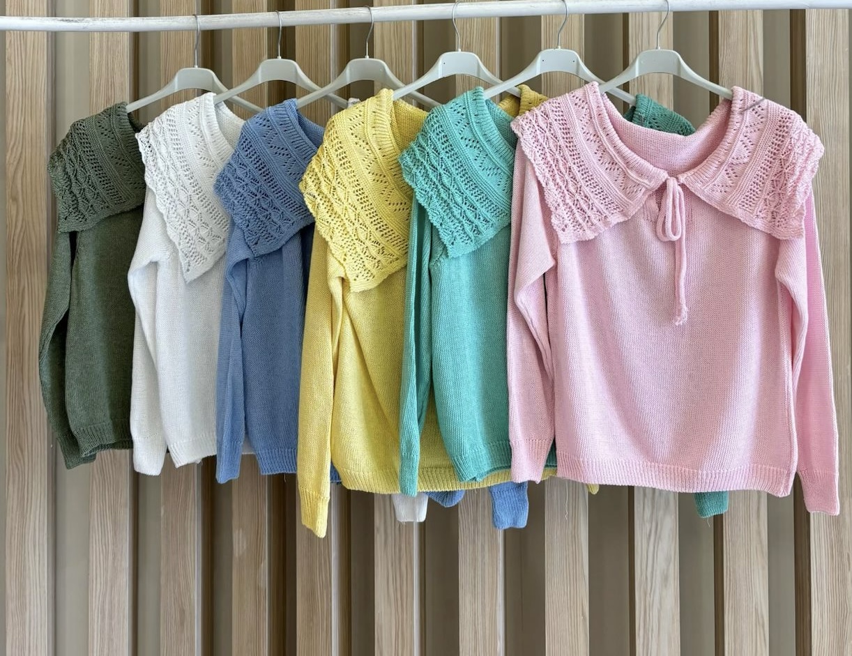 Sete camisolas coloridas de malha com gola rendada penduradas em cabides