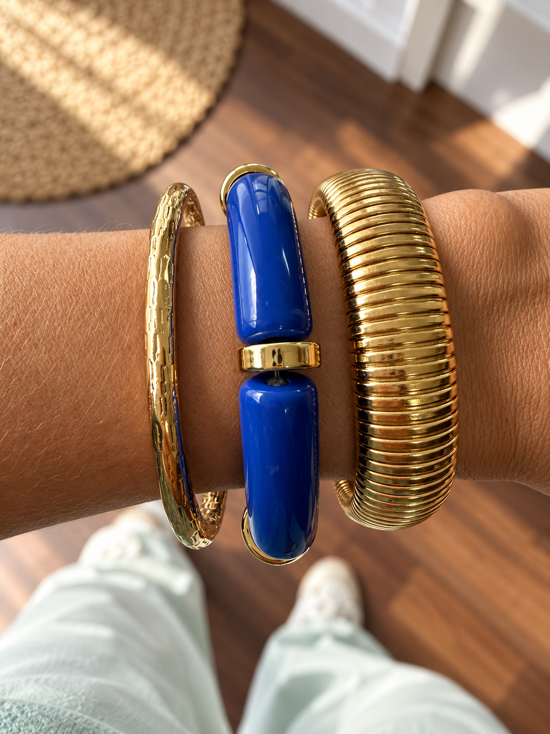 Três pulseiras douradas e azul no pulso em ambiente interior