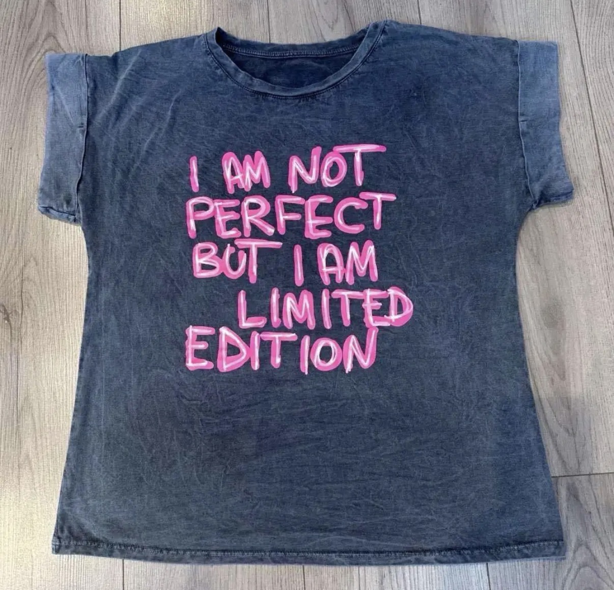 T-shirt preta com texto rosa laid on wooden floor
