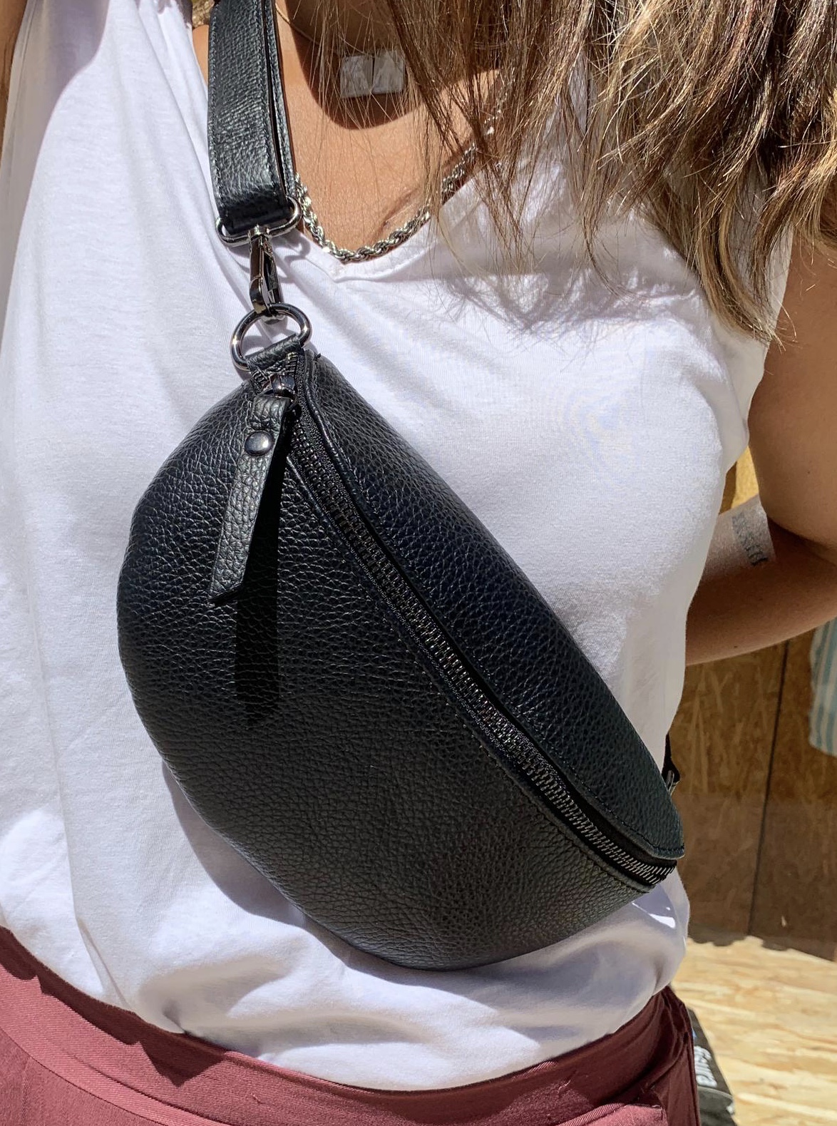 Bolsa de ombro preta em couro com textura granulada e fecho de correr preto