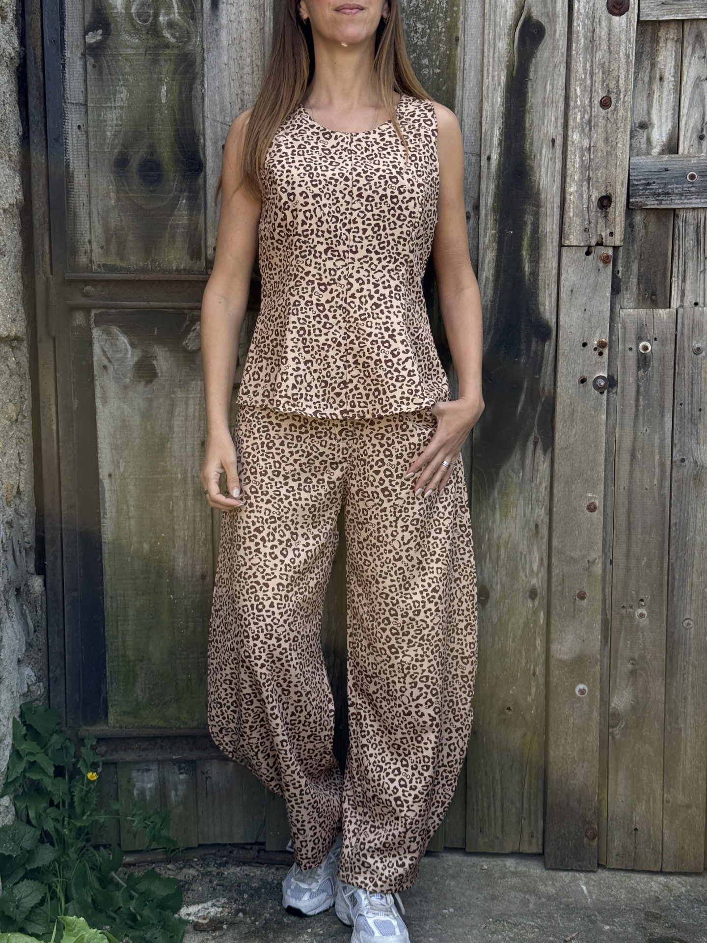 Conjunto de roupa com padrão leopardo, mulher em pé junto a porta de madeira