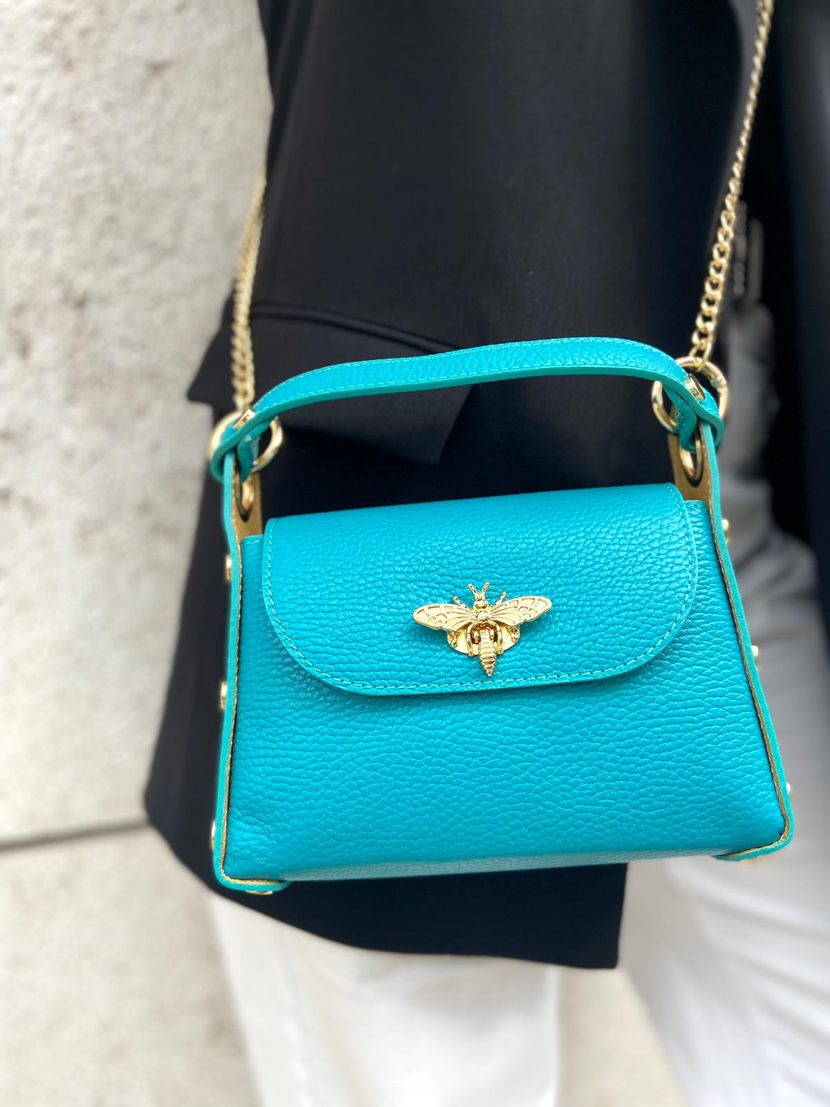 Mala pequena azul turquesa em couro com alça dourada e fecho em abelha