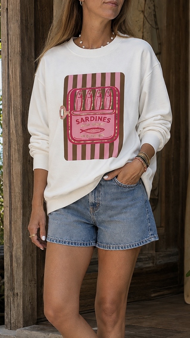 Mulher vestindo sweatshirt branca com estampa de lata de sardinhas cor-de-rosa e calções de ganga.