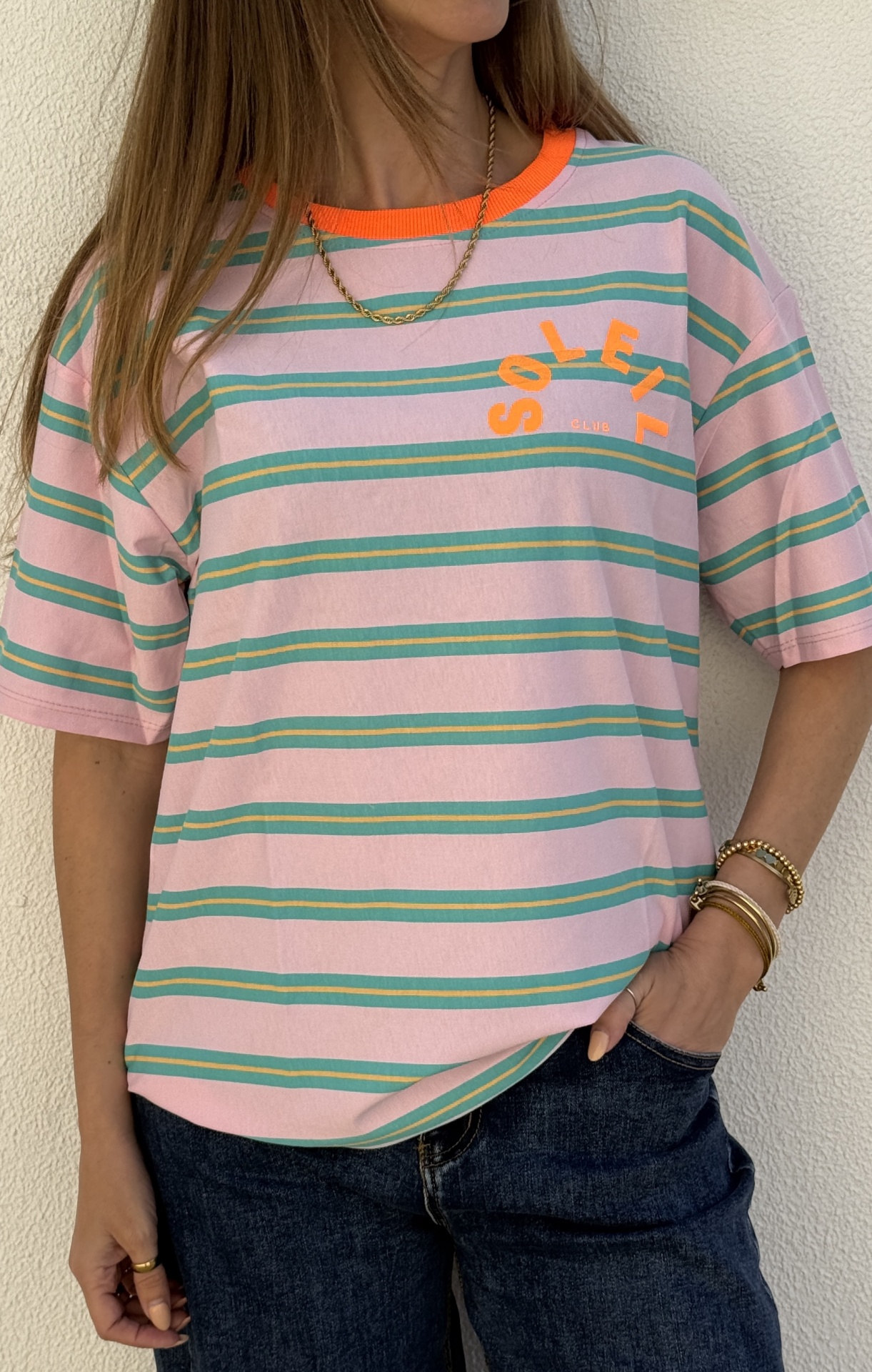T-shirt rosa com riscas verdes e amarelas e gola laranja