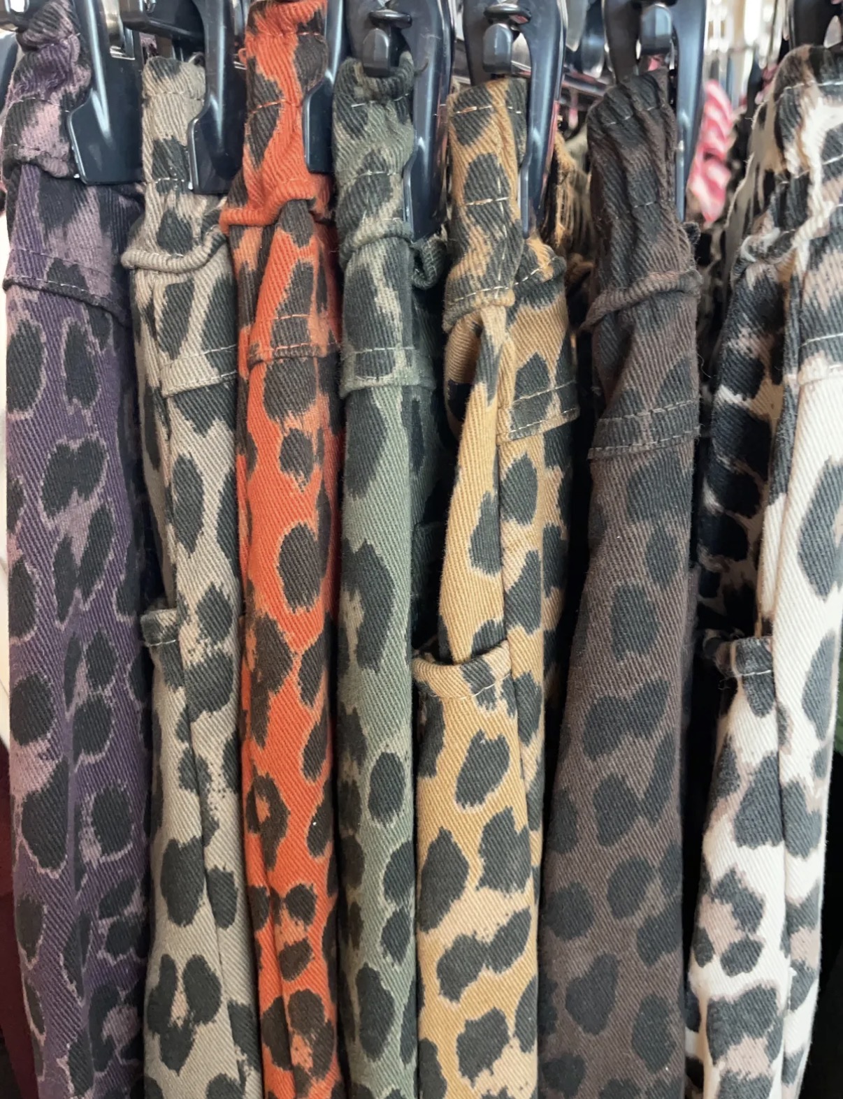 Camisas com padrão animal print de várias cores penduradas em cabides pretos