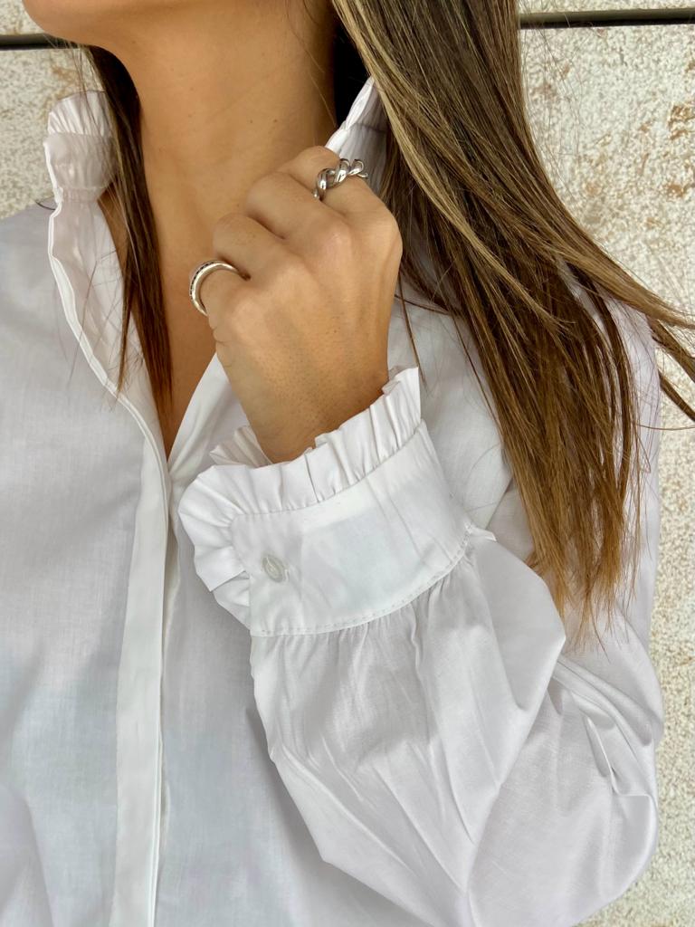 Pessoa com camisa branca e anéis prateados