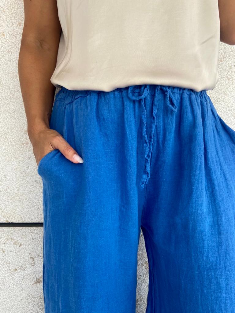 Calças azuis com bolso lateral e cordão na cintura, com parte superior bege