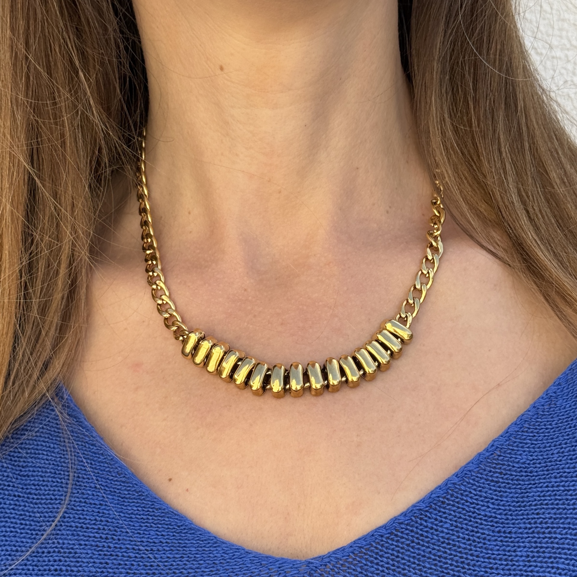 Colar dourado com lâminas penduradas no pescoço