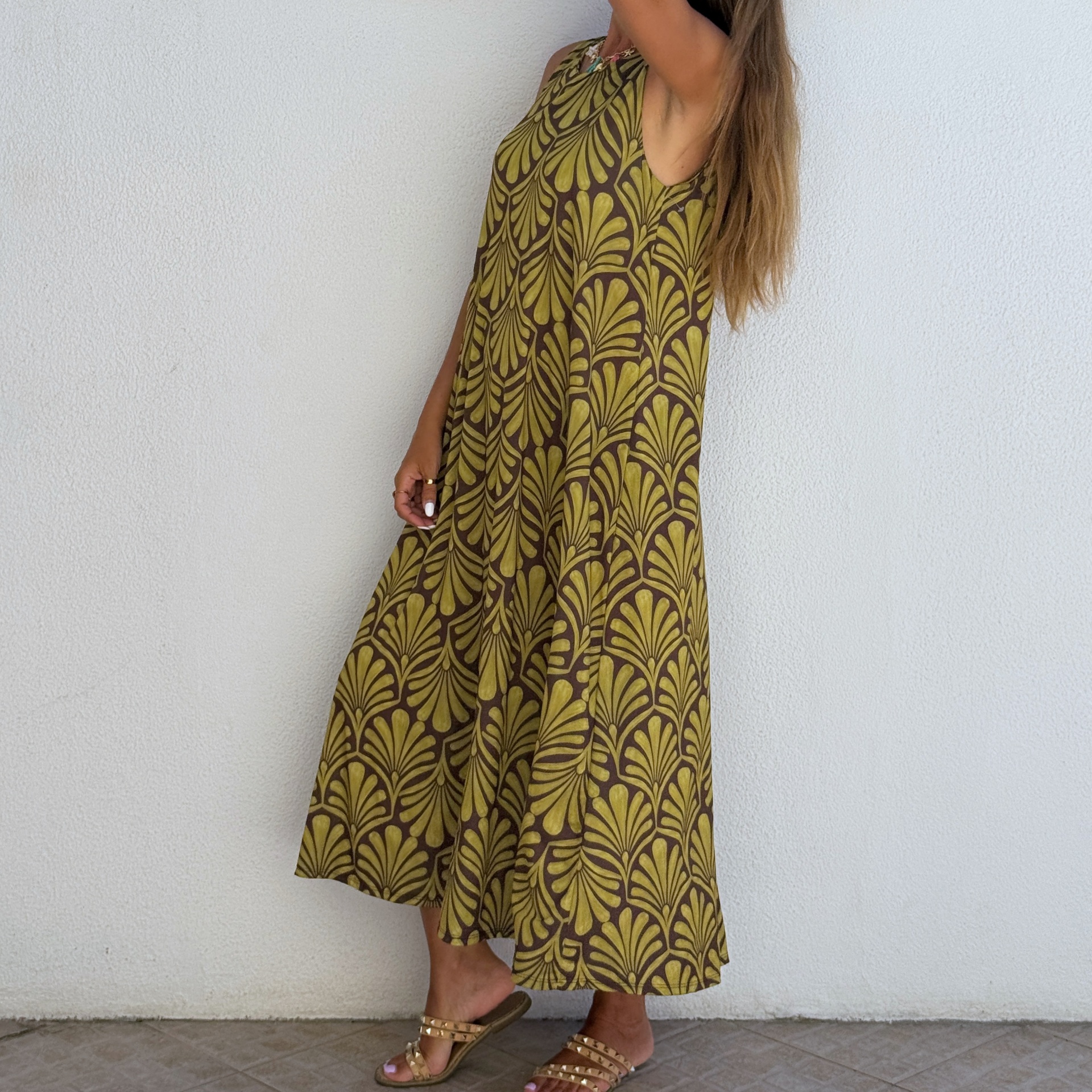 Vestido longo verde e castanho com padrão folhoso e sandálias bege com tachas