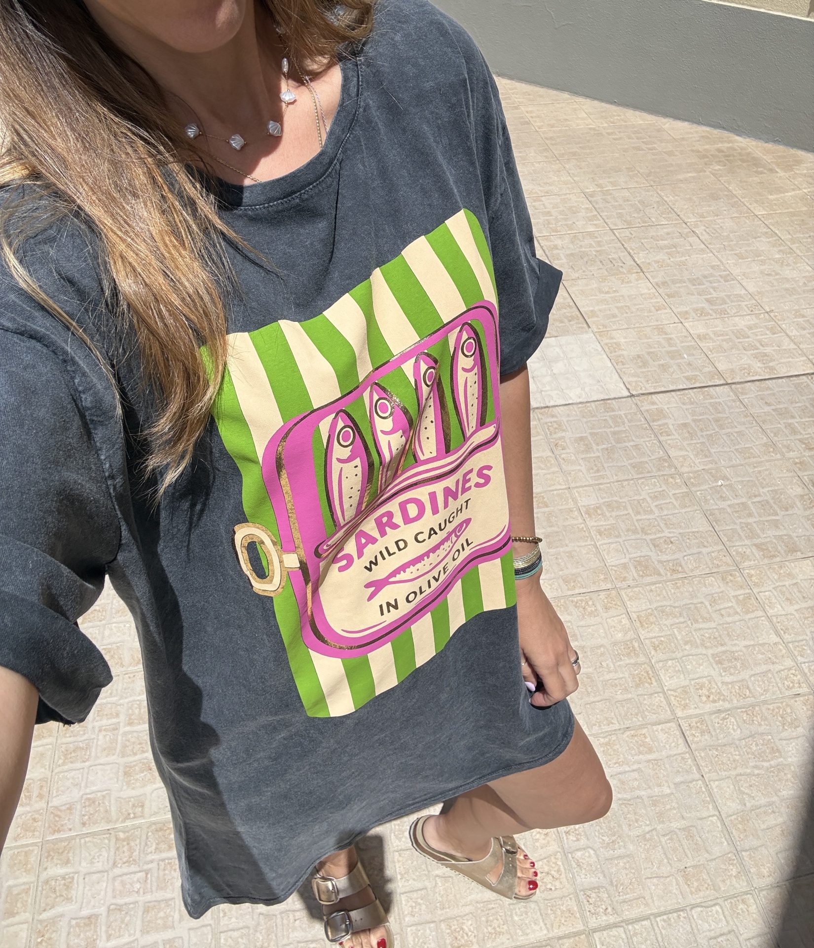 T-shirt cinzenta escura com estampa de peixe e texto e sandálias douradas