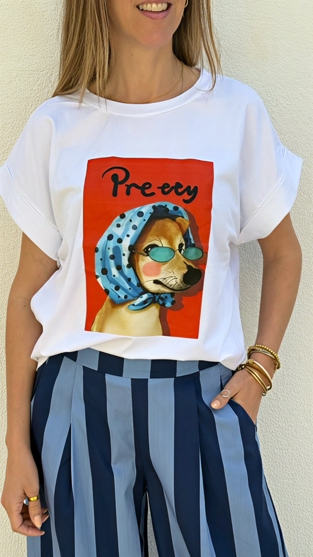 T-shirt branca com estampa de cão com lenço azul e óculos, calças de riscas azuis.