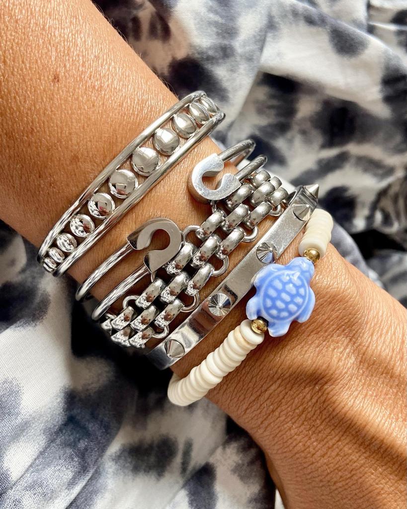 Pulseiras metálicas e de contas com pendente de tartaruga azul no pulso