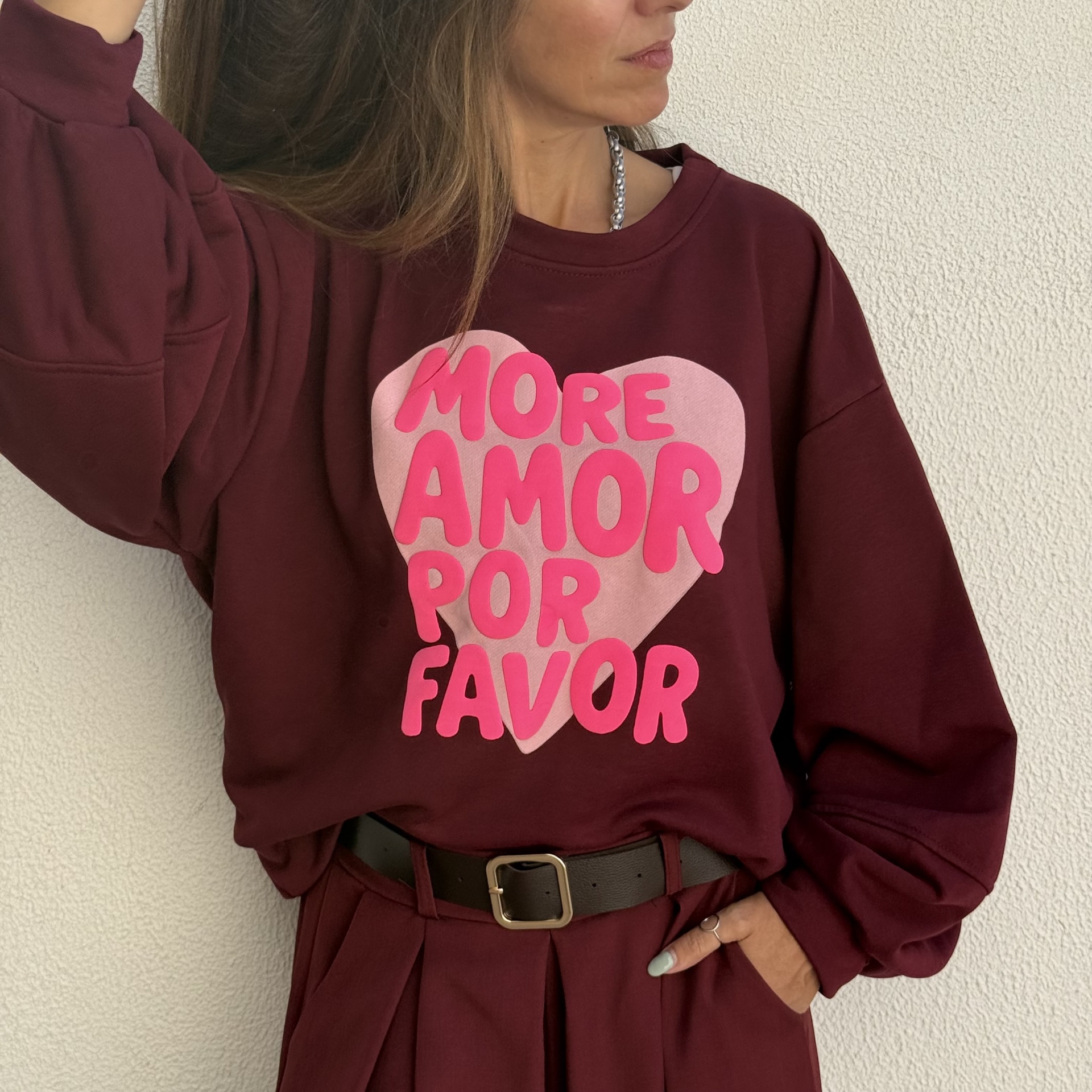 Mulher com sweatshirt vinho com coração rosa com texto MORE AMOR POR FAVOR