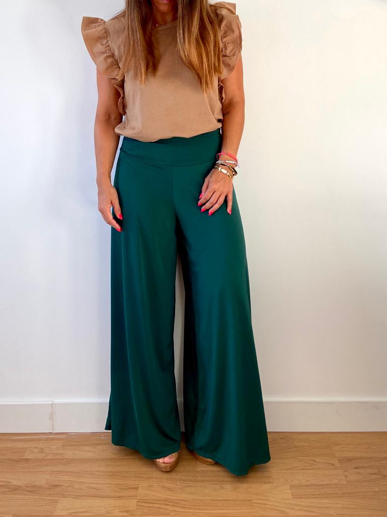 Calças verdes largas com blusa castanho claro em interior