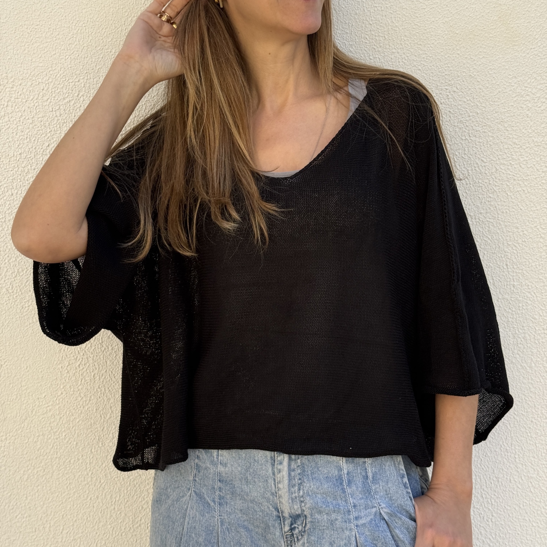 Camisa preta de malha fina com mangas largas e calças de ganga claras.