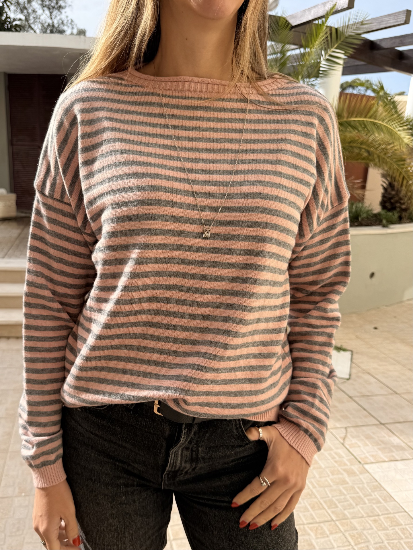 Camisola de malha rosa e cinzento riscada com calças pretas e colar prateado