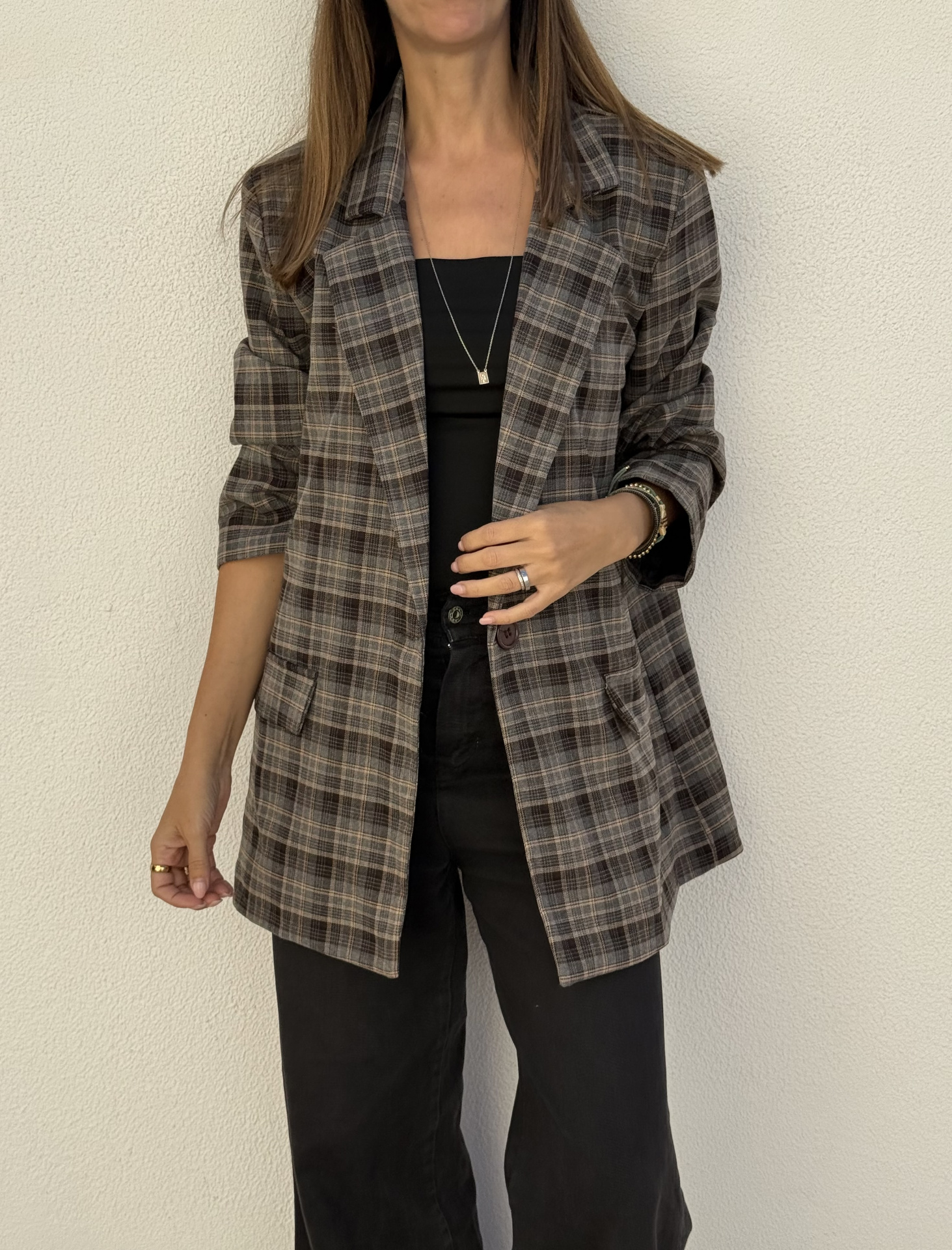 Blazer xadrez em tons castanhos usado por mulher com top preto e calças pretas