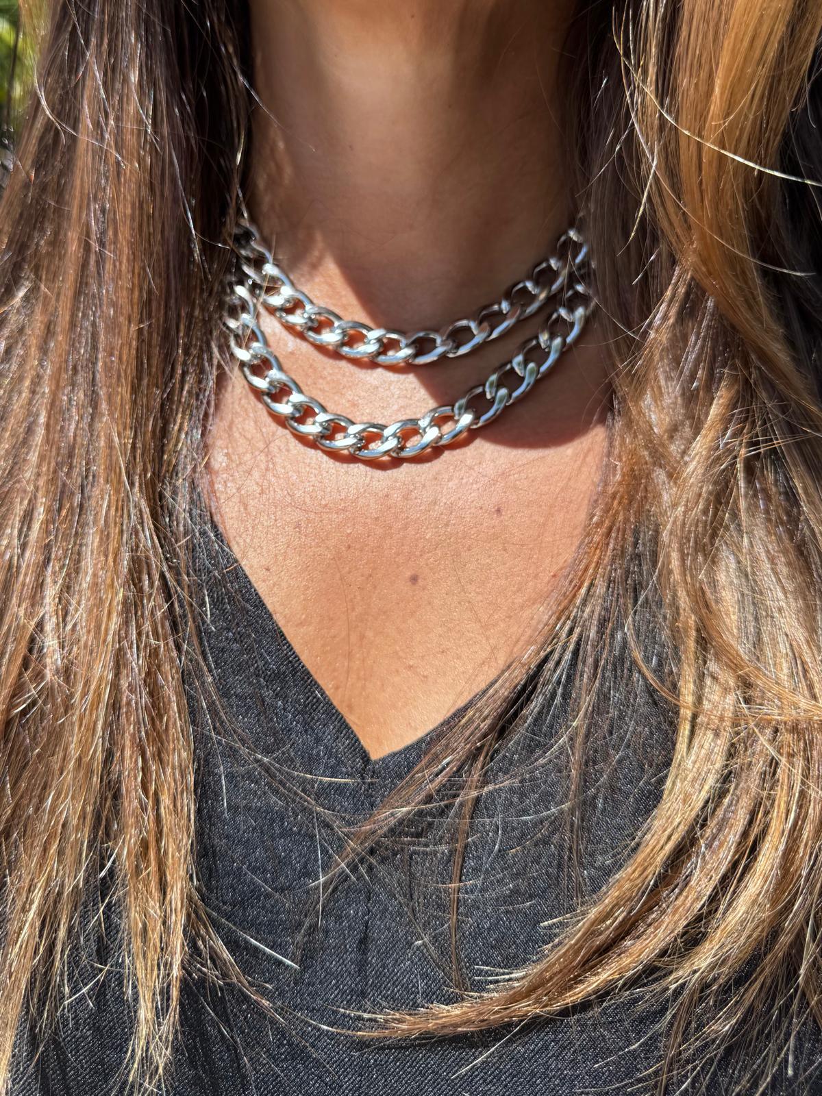 Colar duplo de elos grossos em metal prateado numa pessoa com camisa preta