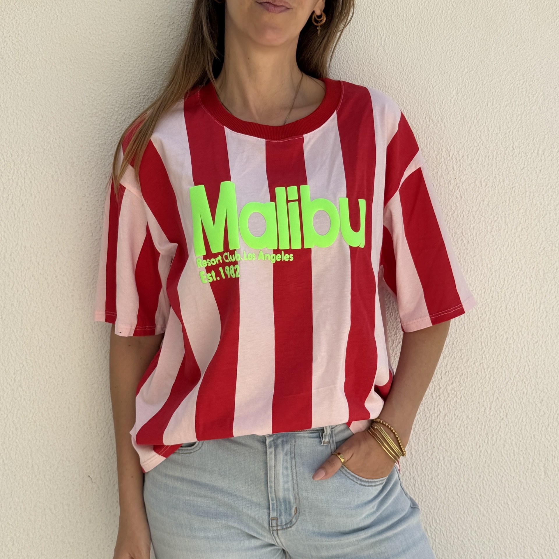T-shirt de riscas vermelhas e rosas com texto verde fluorescente Malibu.