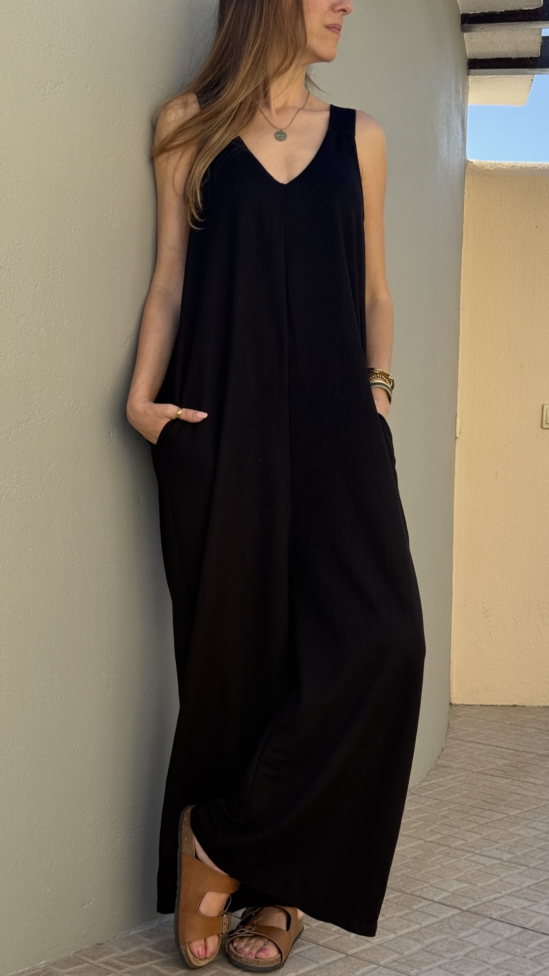 Vestido preto comprido com decote em V e sandálias castanhas