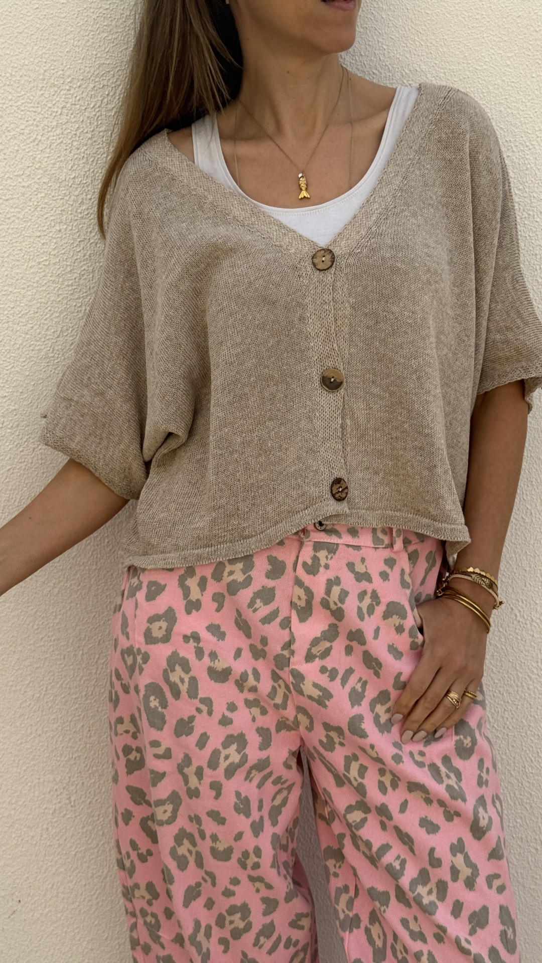 Camisola bege de malha com botões e calças rosa com padrão animal print.