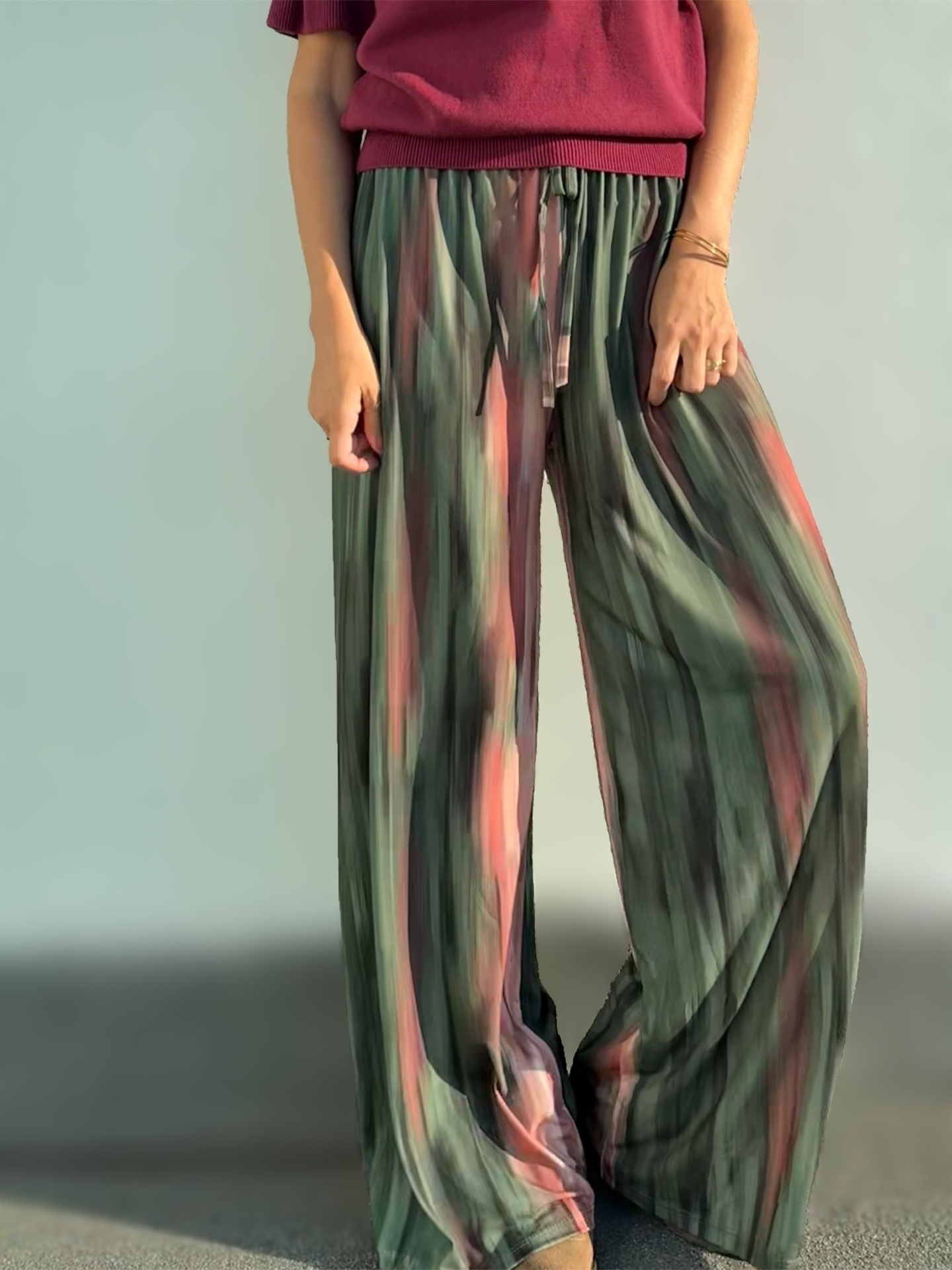 Calças largas de tecido leve com padrão de listas verticais nas cores verde, rosa e cinza.