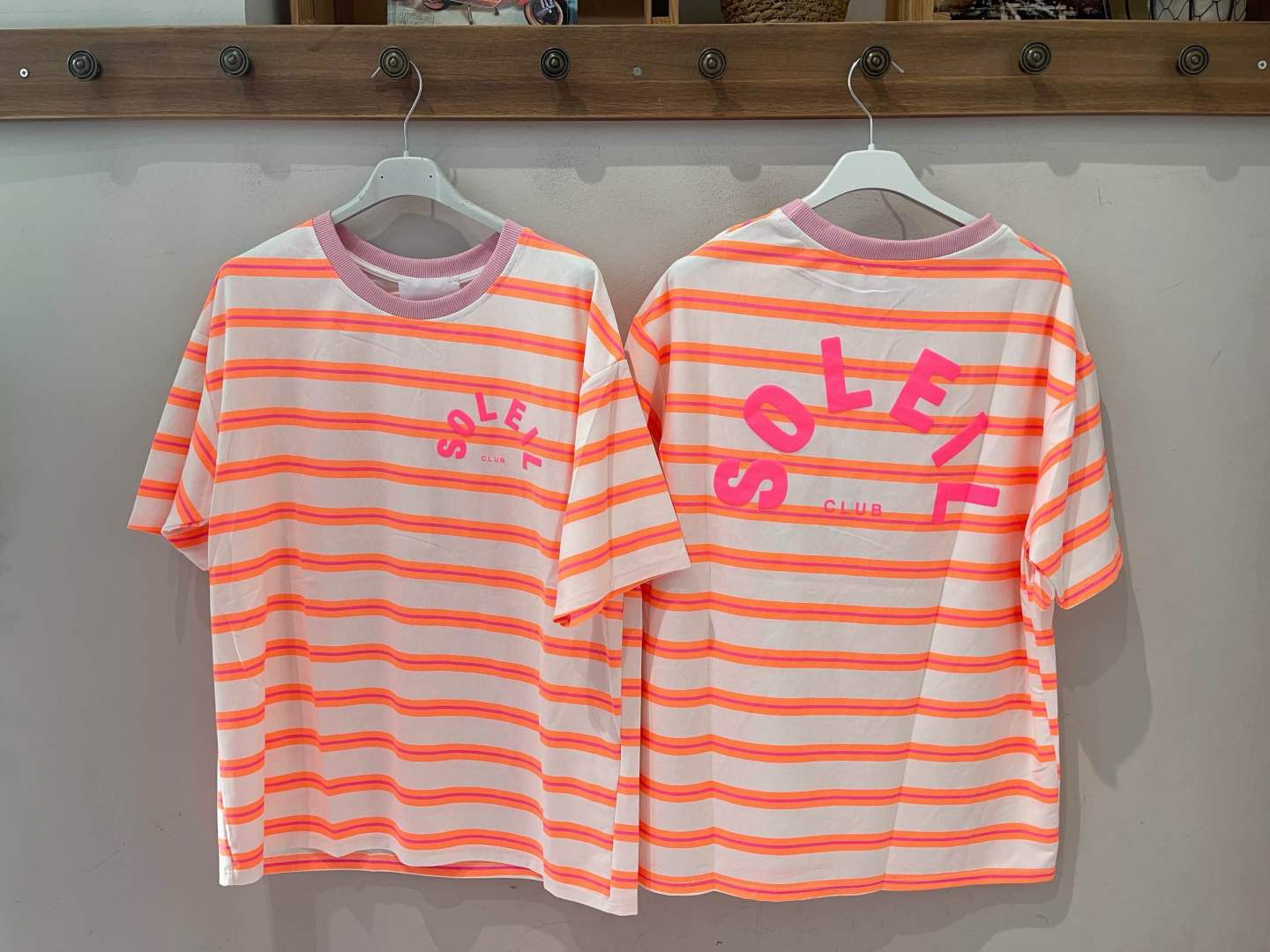 T-shirts riscas laranja e rosa com texto SOLEIL CLUB.