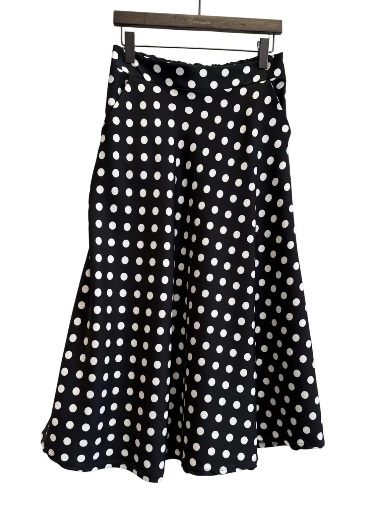 Saia preta com bolinhas brancas pendurada num cabide