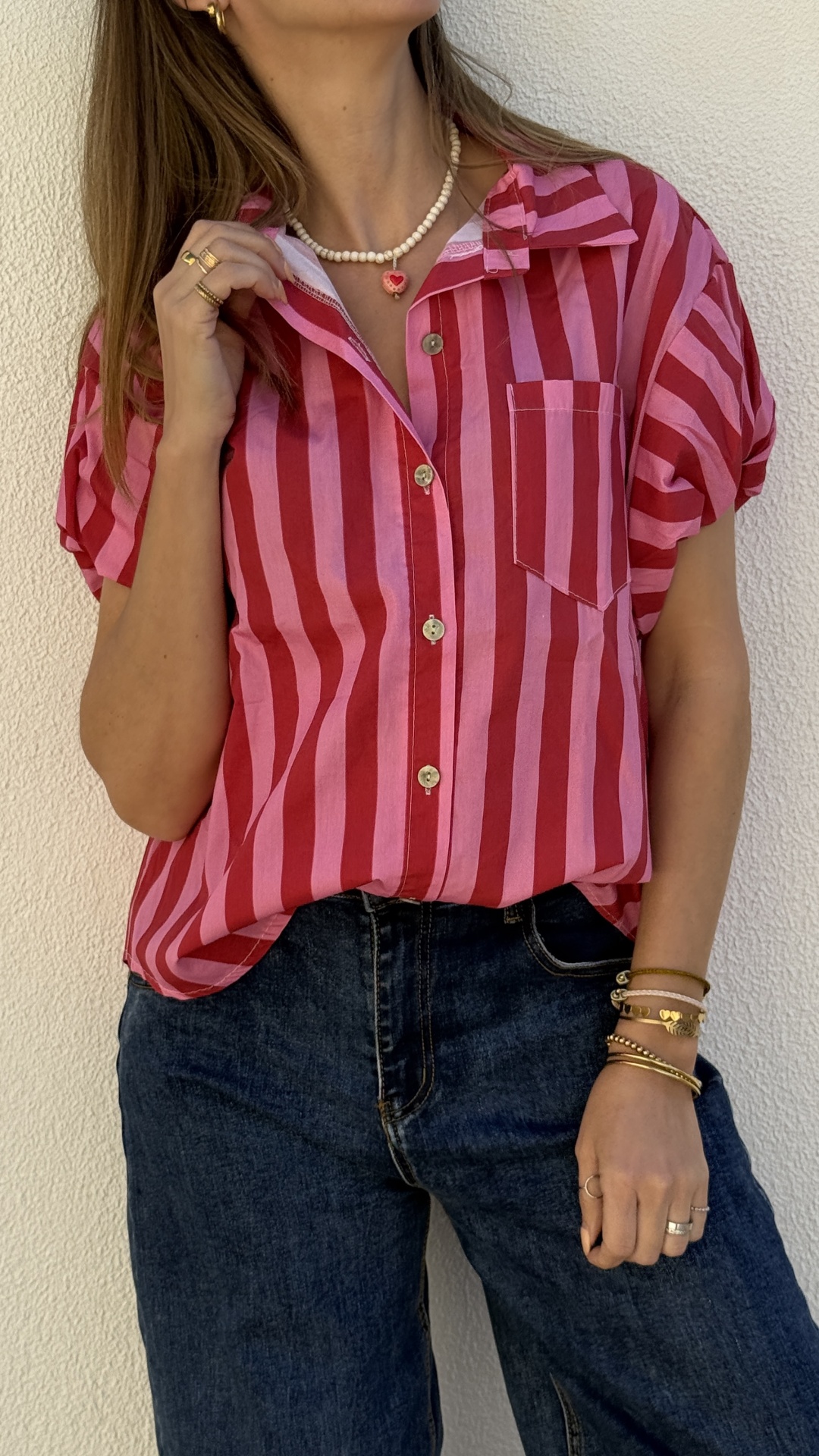 Blusa com riscas verticais rosa e vermelha e jeans azul escuro