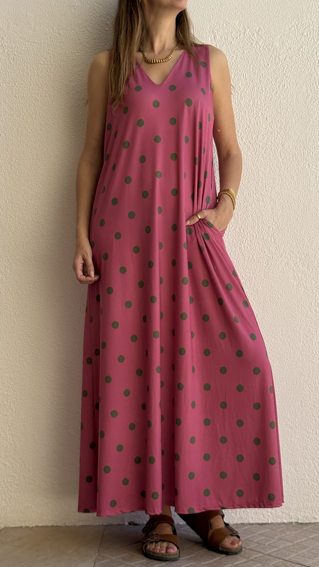Vestido rosa comprido com bolinhas verdes, sem mangas, com bolso e sandálias castanhas