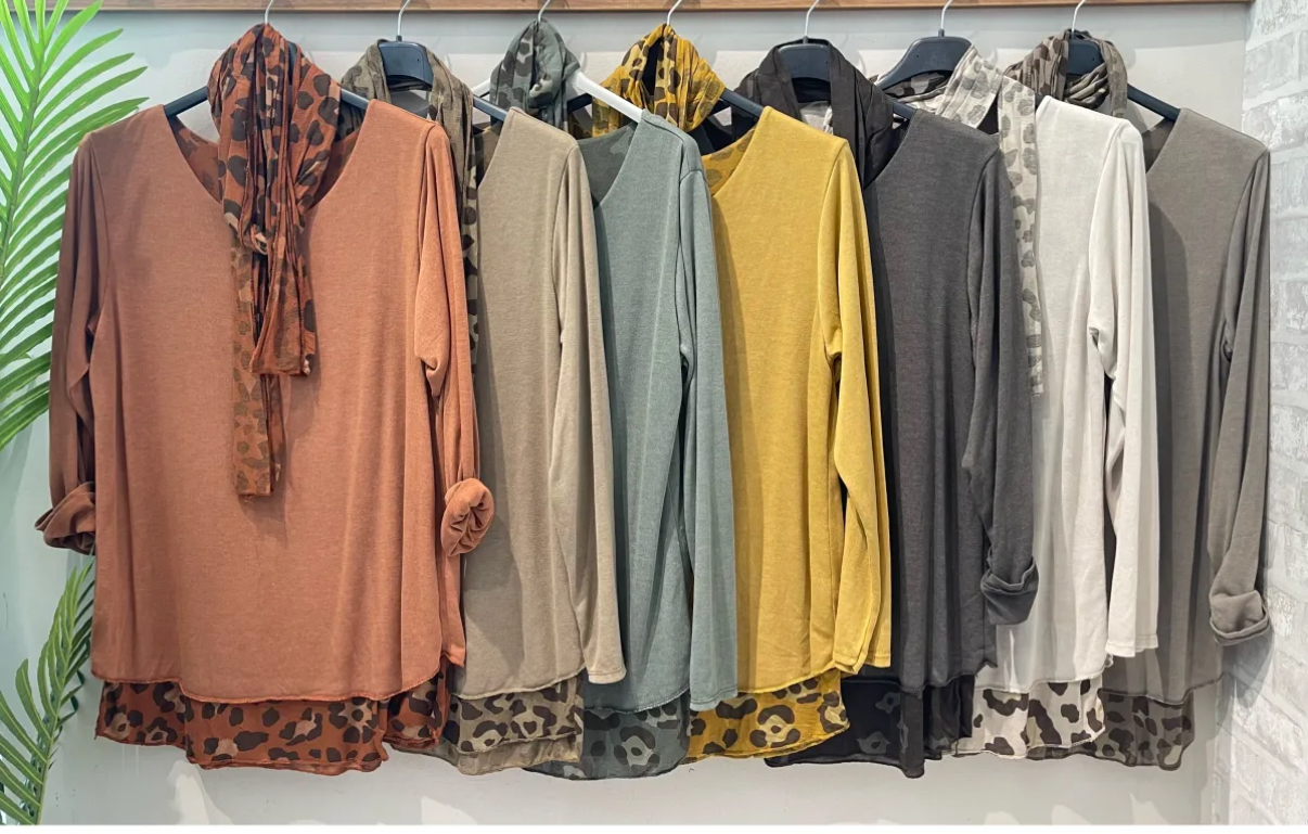 Seis blusas femininas de manga comprida em várias cores com padrão animal print na barra, penduradas num cabideiro