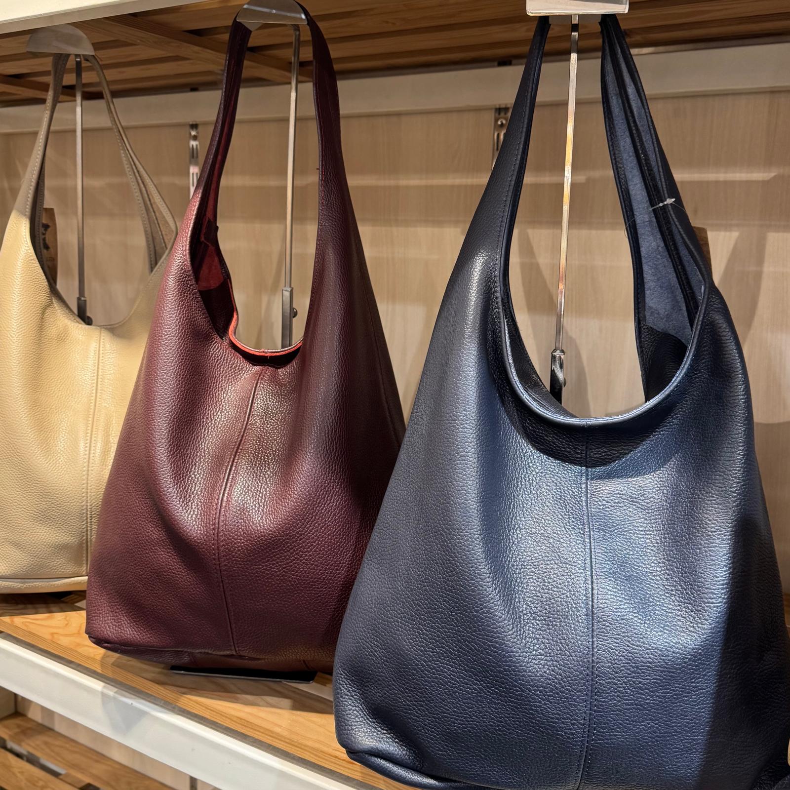 Três malas de pele penduradas numa prateleira de madeira